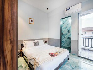 A hotel room with a bed, a nightstand, a picture on the wall, an air conditioning unit, and a bathroom with a marble wall. - Palette Ventara Escape Bunglow Pvt Pool (Lonavala)