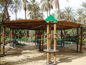 A wooden structure with a rope maze, surrounded by palm trees.