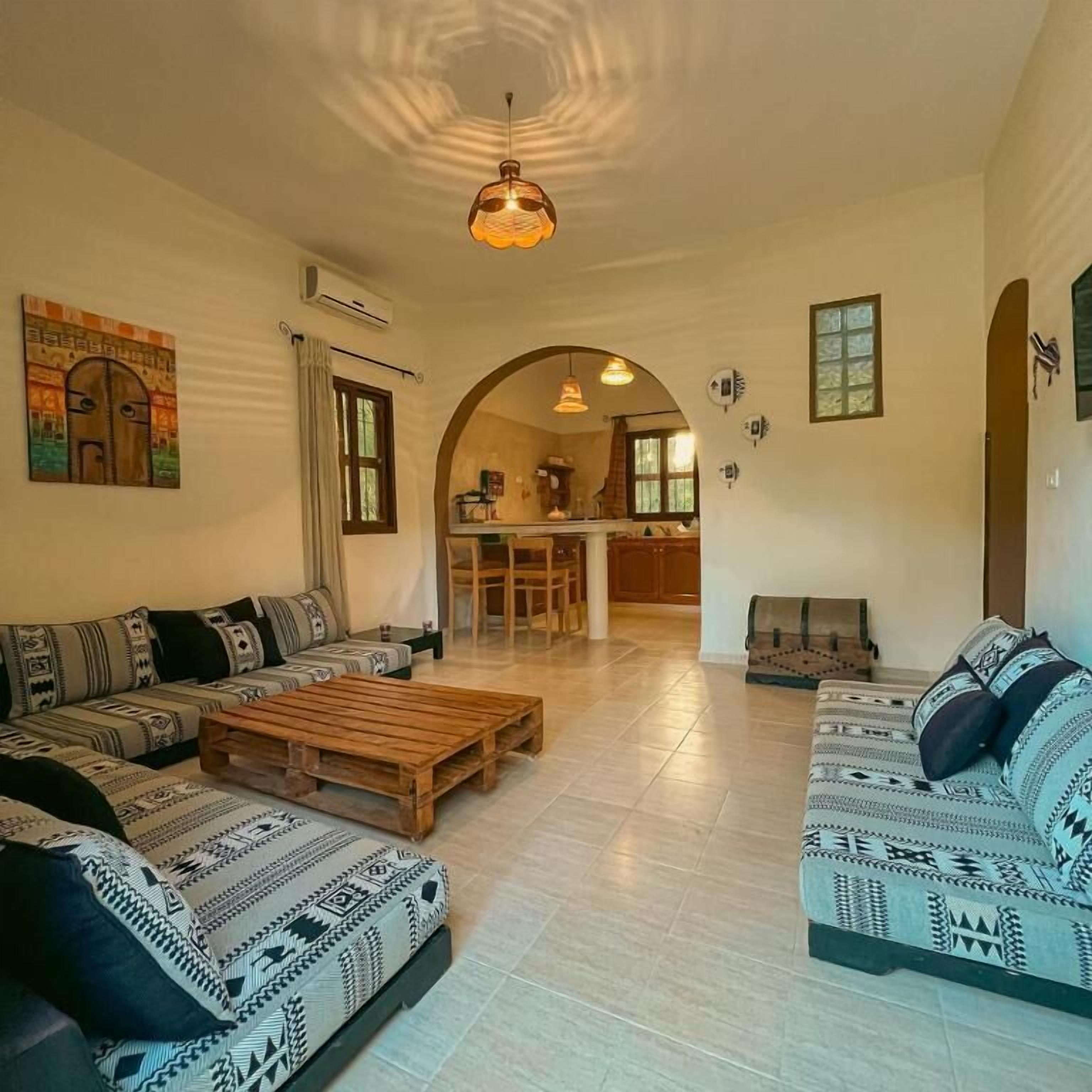 A spacious living area with a sofa set, a wooden coffee table, and a hanging light fixture.