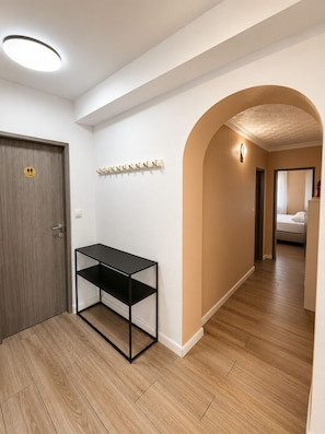 A hallway with a wooden door, a black metal console table, a coat rack, and a bed visible through an archway. - Spacious 3-bedroom apartment in gorgeous Podstrana (Podstrana - Sv. Martin)