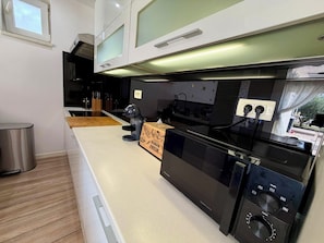 A modern kitchen with a black oven, a wooden cutting board, and a stainless steel trash can. - Spacious 3-bedroom apartment in gorgeous Podstrana (Podstrana - Sv. Martin)