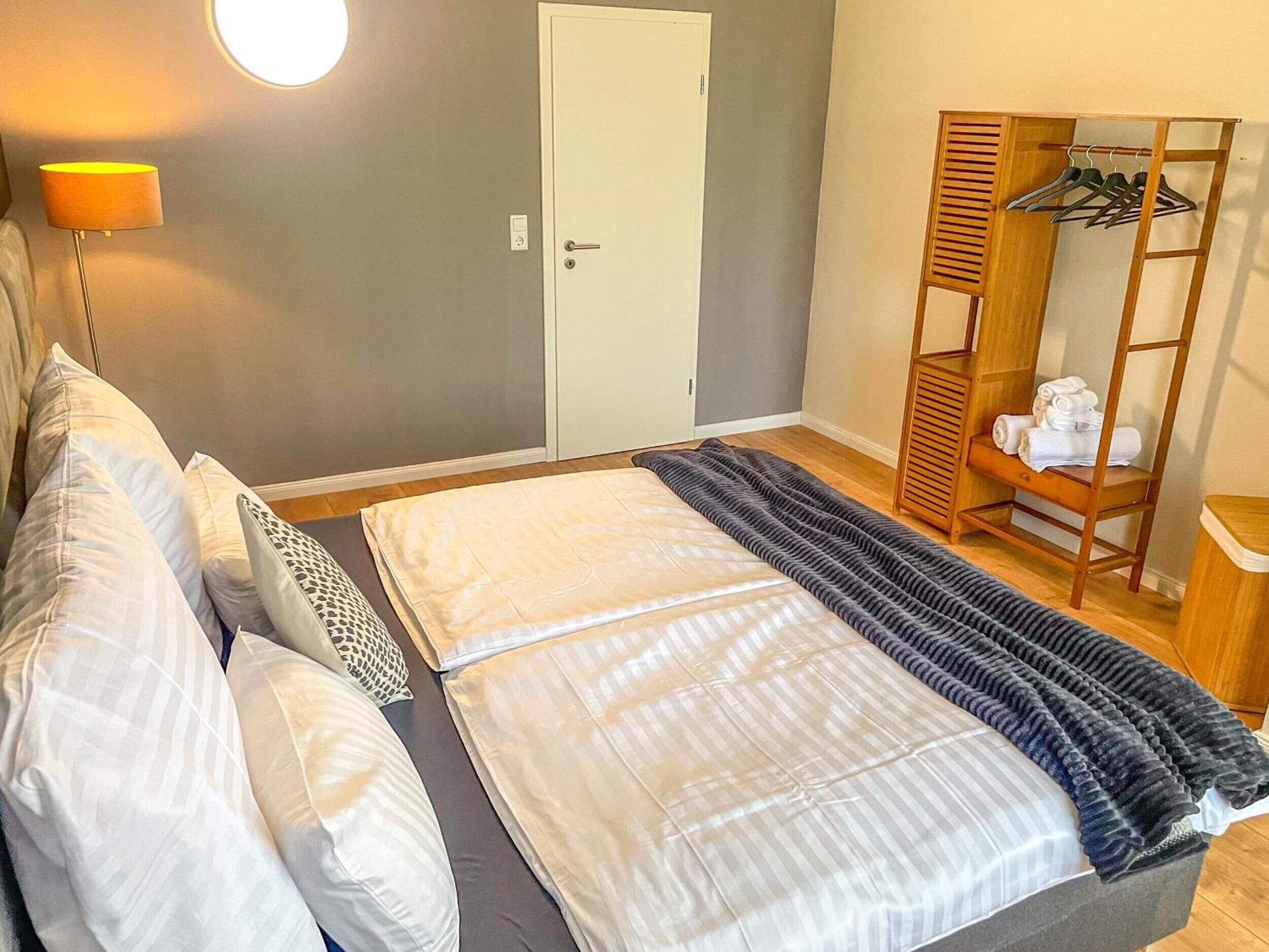 Et soveværelse med seng, garderobeskab, lampe og spejl.