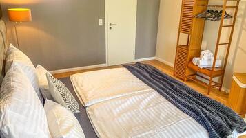 Et soveværelse med seng, garderobeskab, lampe og spejl.