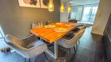 Un comedor moderno con una mesa de madera, sillas tapizadas en gris e iluminación colgante.