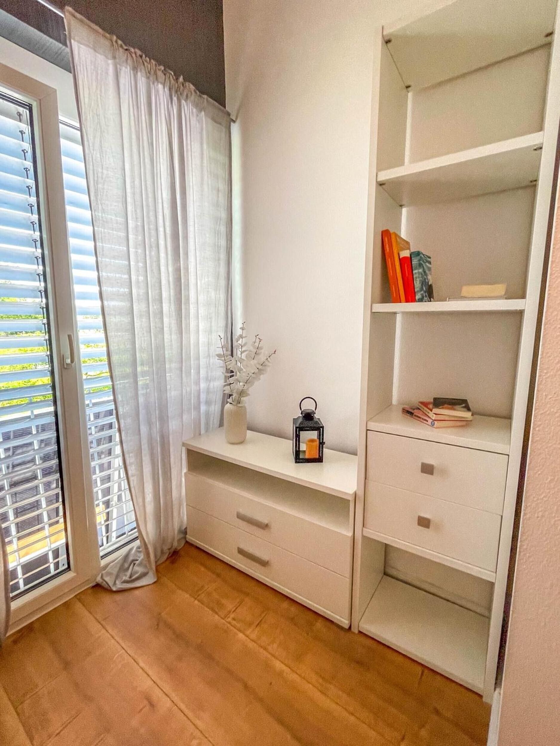 A room with a sliding glass door, a white console table, and a built-in shelving unit with books and decorative items.