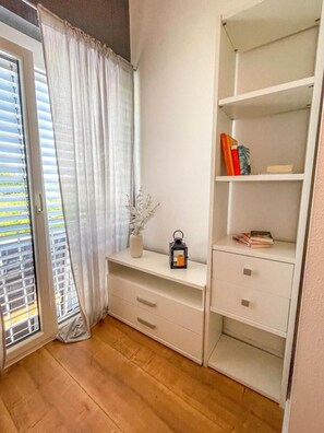 A room with a sliding glass door, a white console table, and a built-in shelving unit with books and decorative items. - Modern Luxury Villa Antonia (Mössingen)