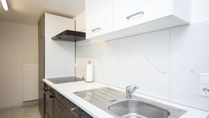Una cucina moderna con lavello in acciaio inossidabile, mobili bianchi e piano di lavoro in marmo.