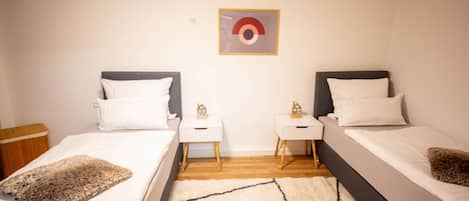 A double room with two beds, nightstands, a rug, and a wall-mounted picture.