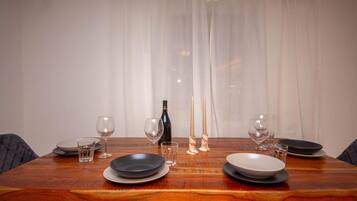 Una mesa de comedor dispuesta con platos, vasos y velas, con una botella y un candelabro sobre la mesa.
