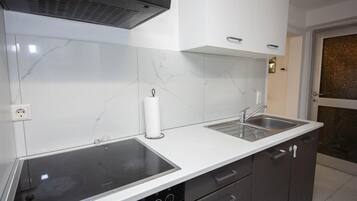 Una cocina moderna con estufa integrada, dos fregaderos y un salpicadero de mármol blanco.