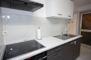 A modern kitchen with a built-in stove, two sinks, and a white marble backsplash.