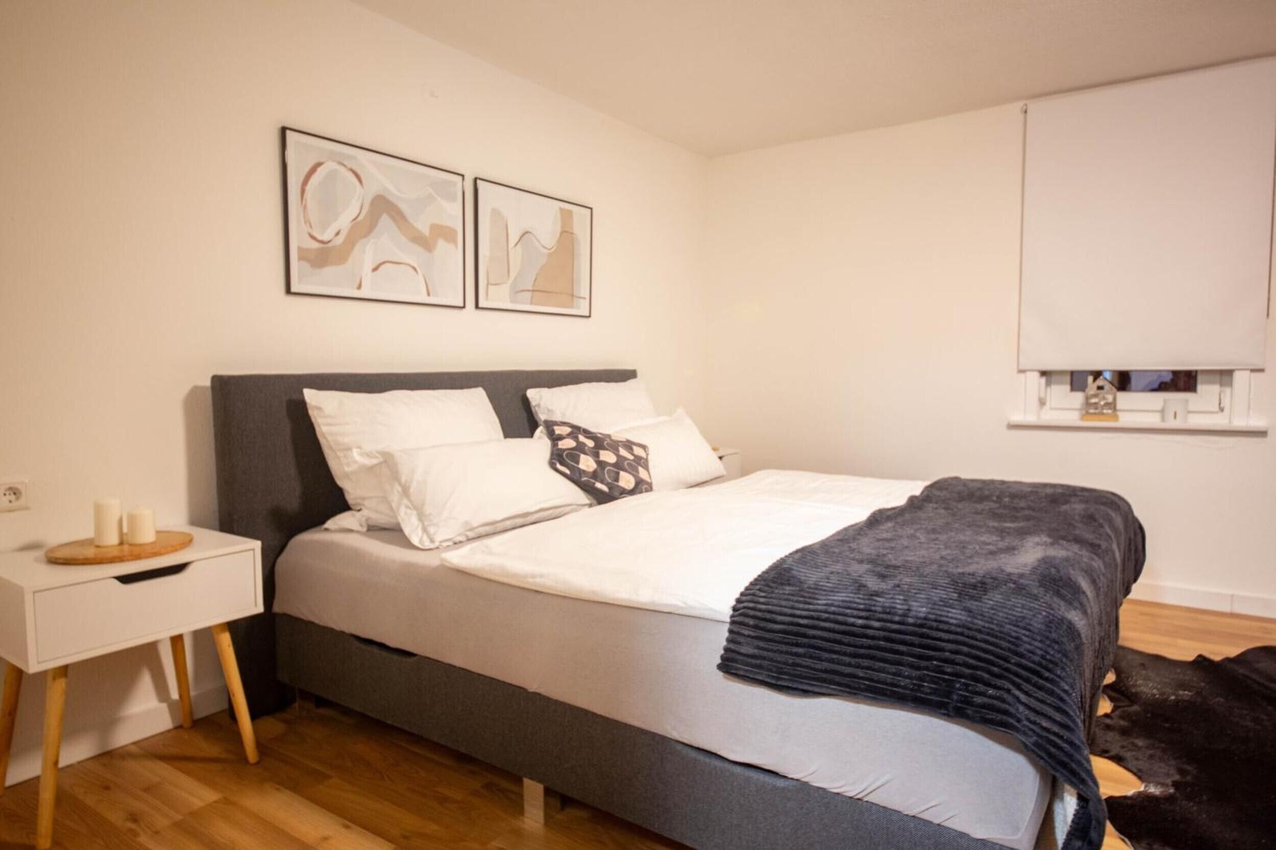 Une chambre à coucher avec un lit, une table de chevet et une étagère fixée au mur.