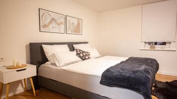 Une chambre à coucher avec un lit, une table de chevet et une étagère fixée au mur.