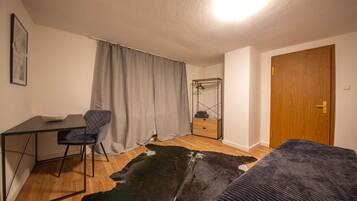 Ein Zimmer mit Schreibtisch, Stuhl, Bett und Spiegel.