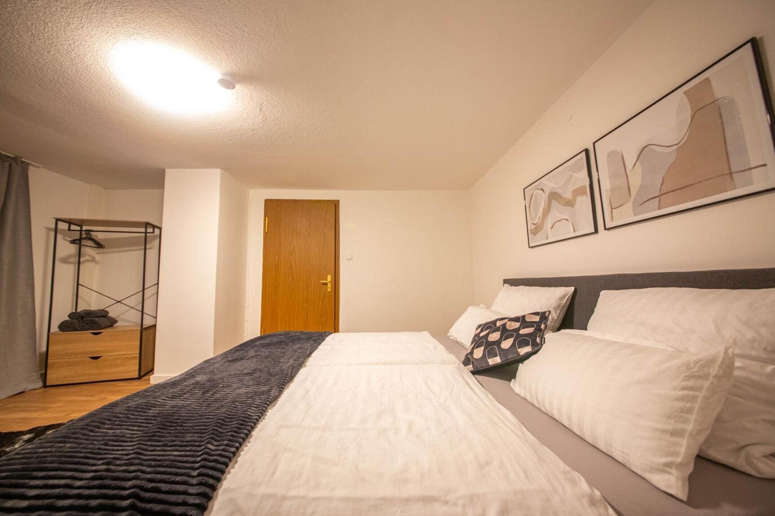 A hotel room with a bed, a wardrobe, a mirror, and artwork on the wall.