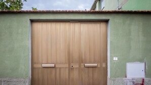 A large, closed wooden door with a green wall and a tiled roof. - An elegant suite within a multi-unit property, ideal for two guests, featuring ground-floor access (with a single step at the entrance).The property is located in the center of Selargius—a town situated approximately 6.5 km from Cagliari’s city cente (Selargius)