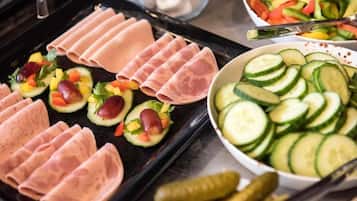 Une table de buffet avec des viandes en tranches, des légumes et des cornichons.