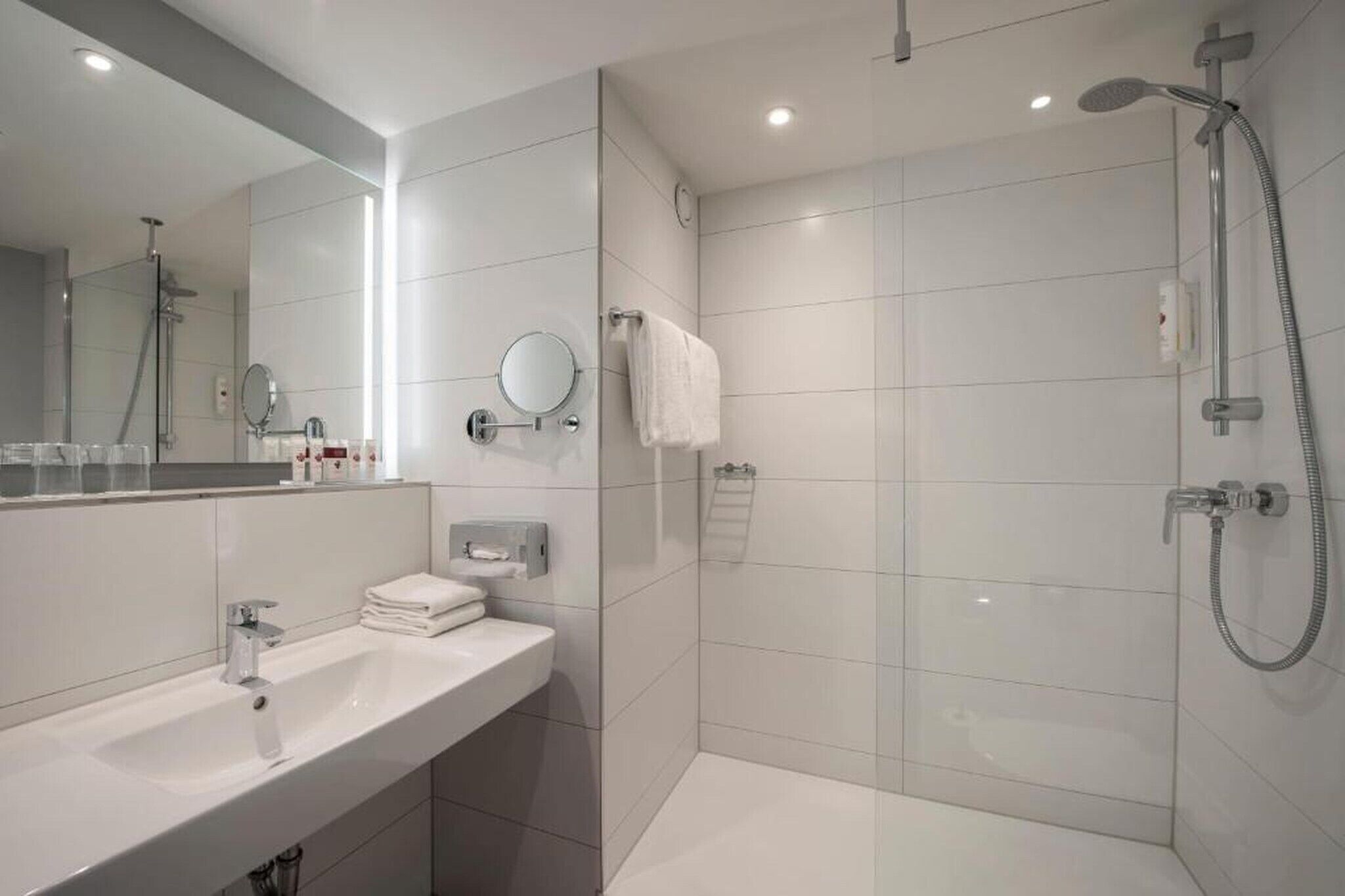 Ein modernes Badezimmer mit Waschbecken, Spiegel und Dusche.