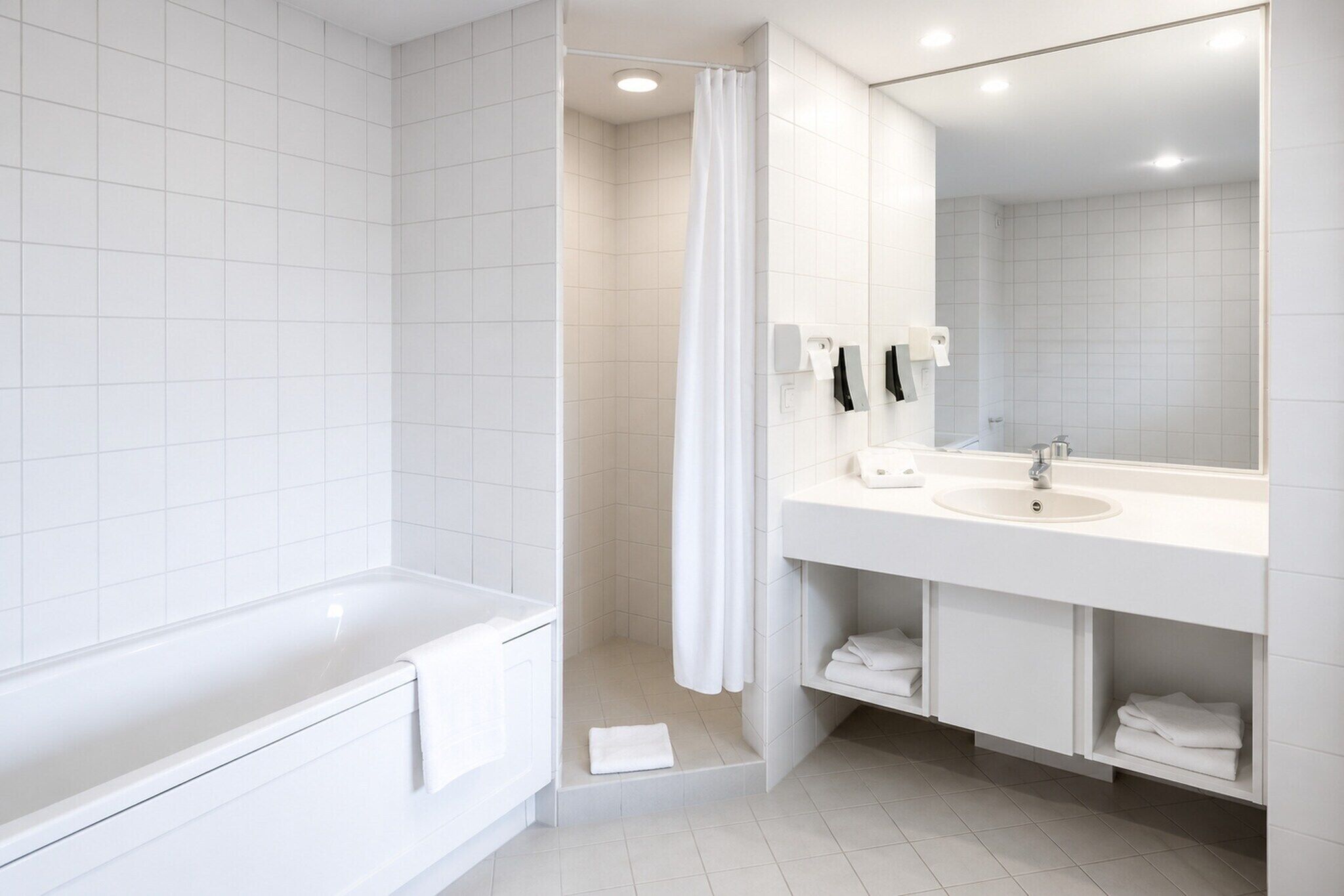 Un baño moderno con bañera, ducha y un espejo grande sobre el lavamanos.