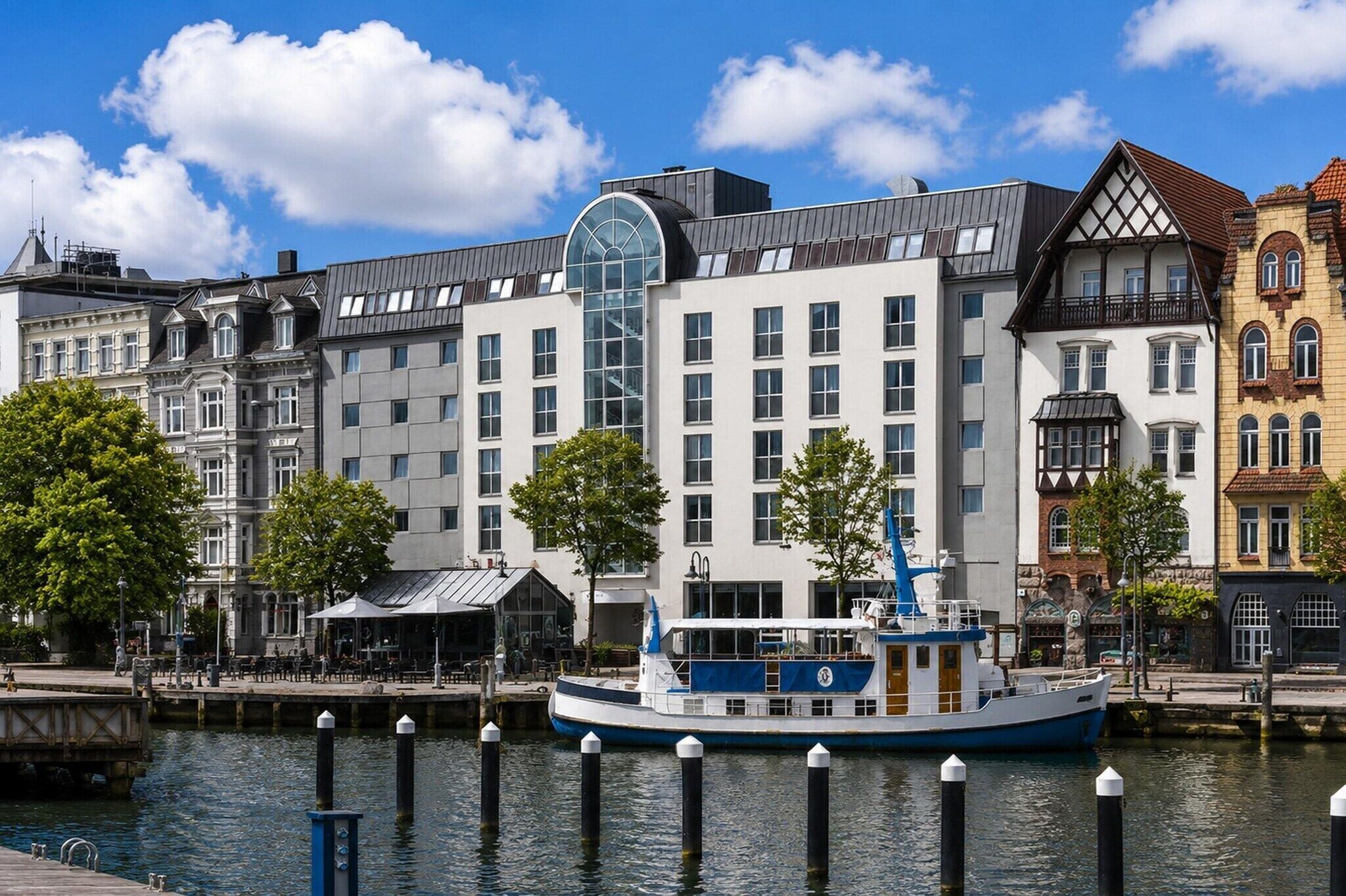 Un hôtel situé au bord de l’eau, doté d’un grand ascenseur en verre, de plusieurs étages et d’un bâtiment de style traditionnel agrémenté d’une tourelle.