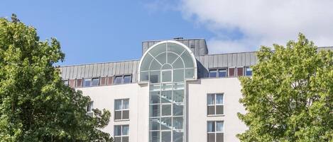 Un edificio moderno con una amplia fachada de vidrio, múltiples ventanas y un elemento circular central.