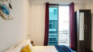 Hotellihuone, jossa on sänky, vaatekaappi, parveke, jolta on näkymä, ja koristeellinen seinäelementti.