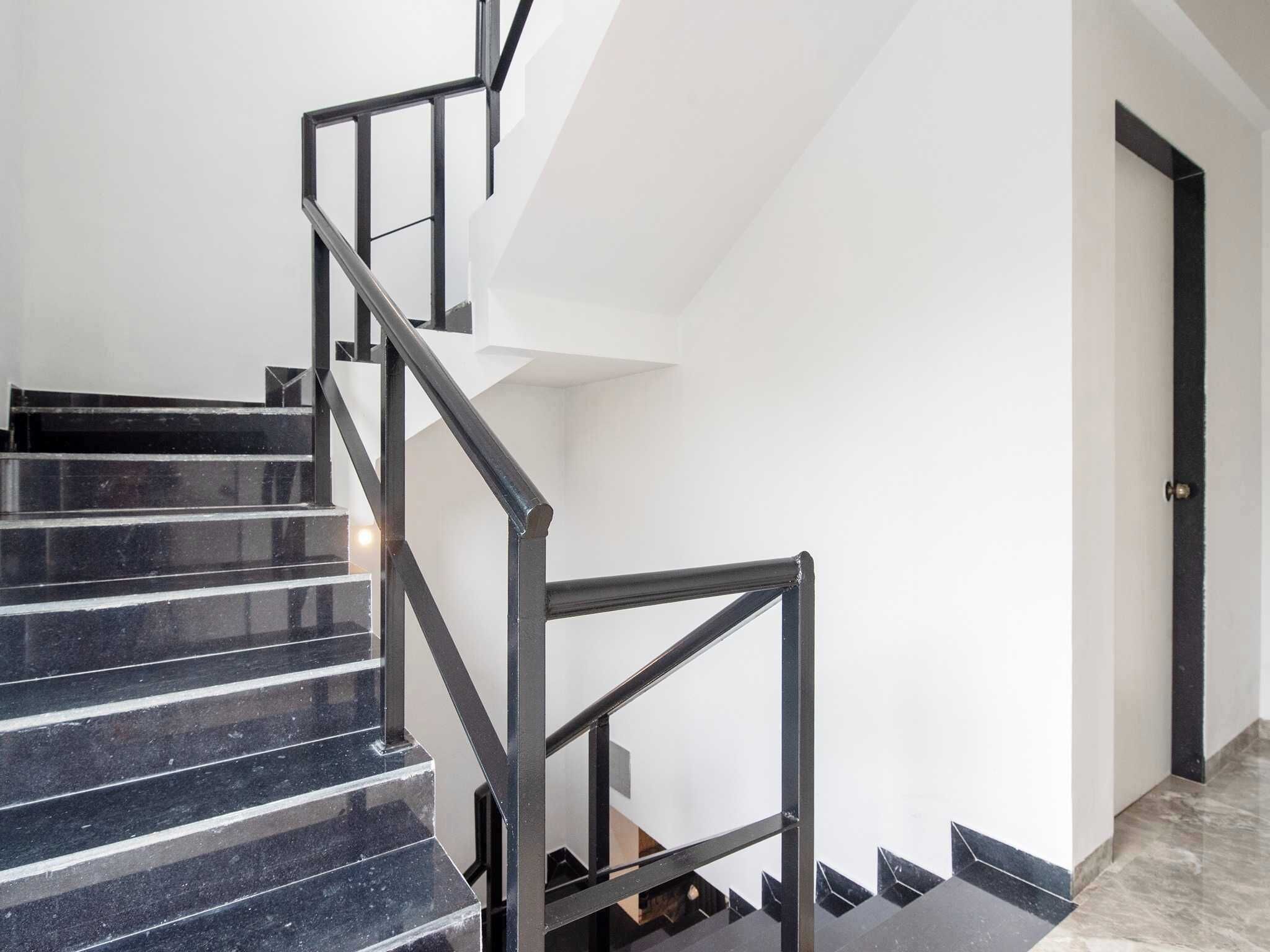 A staircase with black railings and marble steps leading to a door.