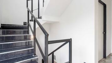 A staircase with black railings and marble steps leading to a door.