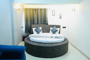 A circular bed with a grey headboard, two pillows, and a white blanket.