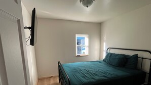 Ein Schlafzimmer mit Bett, Fenster und Deckenleuchte.