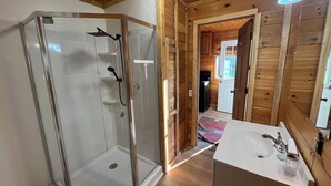 Eine Duschkabine aus Glas mit einem weißen Waschbecken und Holzvertäfelung.
