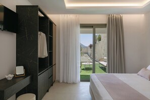 A modern hotel room with a bed, a TV, a wardrobe, and a balcony with a view. - Pyxis Villa, Family Friendly with Heated Pool (Perama)