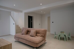 A modern living room with a sofa, a dining table with chairs, and a staircase. - Pyxis Villa, Family Friendly with Heated Pool (Perama)
