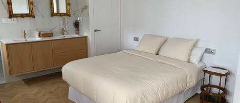 Un dormitorio con una cama, un aparador de madera, un espejo y una mesita de noche.
