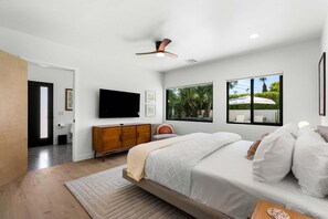 A bedroom with a bed, a TV, a window, and a ceiling fan. - Solstice Sonora - A Ryson Property (Palm Springs)