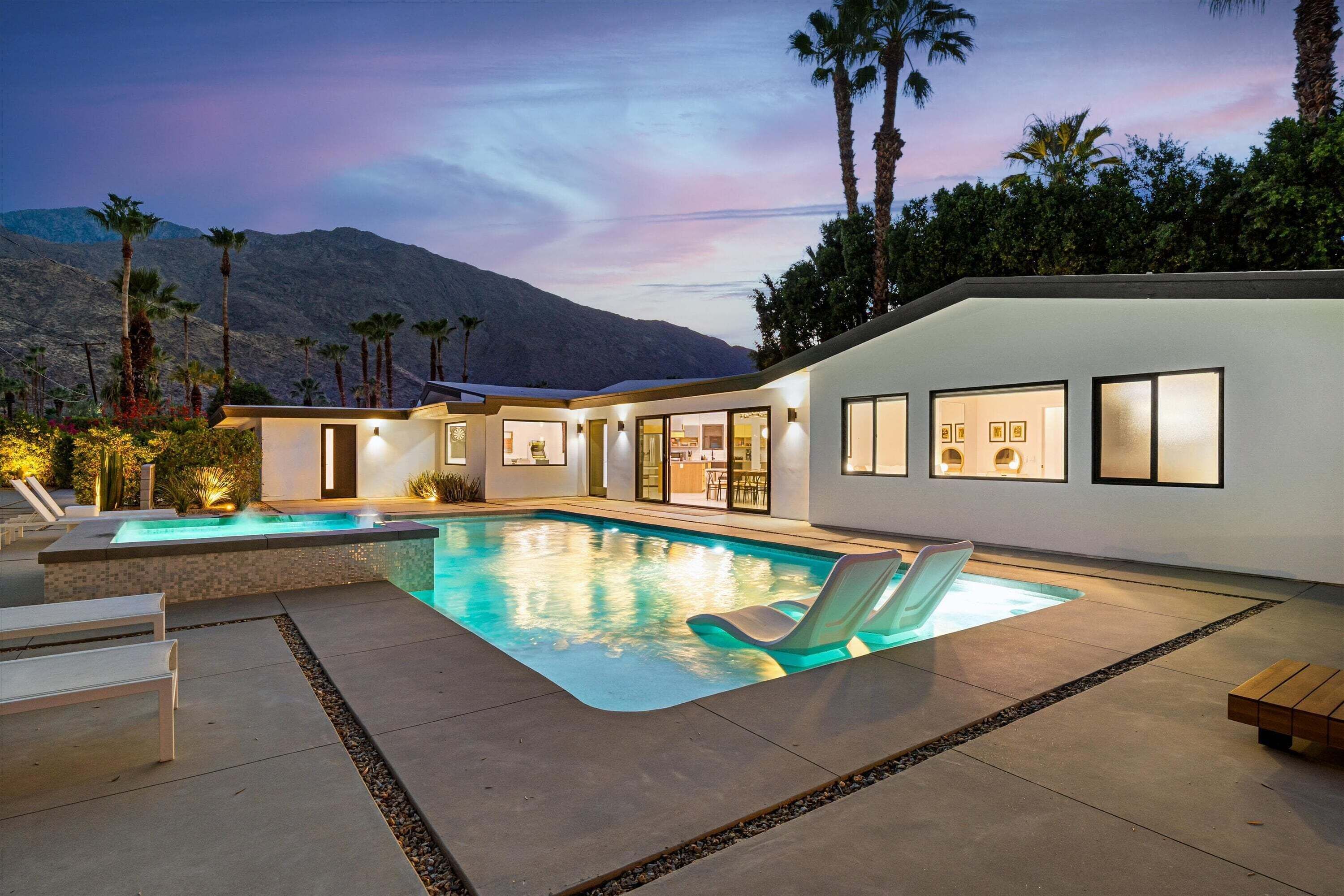 A modern house with a swimming pool, outdoor seating, and a mountain view.