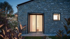 A modern building with a stone facade, a large sliding glass door, and a small window. - MC Como - My Home in Como (Tremezzo)