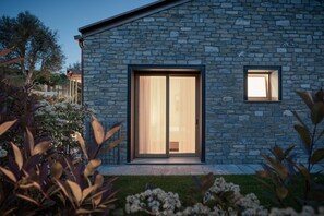 A modern building with a stone facade, a large sliding glass door, and a small window.