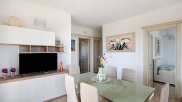 A dining area with a glass table, chairs, a television, and decorative items.