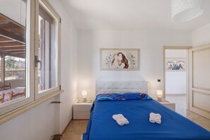 A bedroom with a bed, two bedside lamps, a painting on the wall, and a window with a view of the outside. - Villa 'Adg House' with Shared Terrace, Wi-Fi and Air Conditioning (Otranto)
