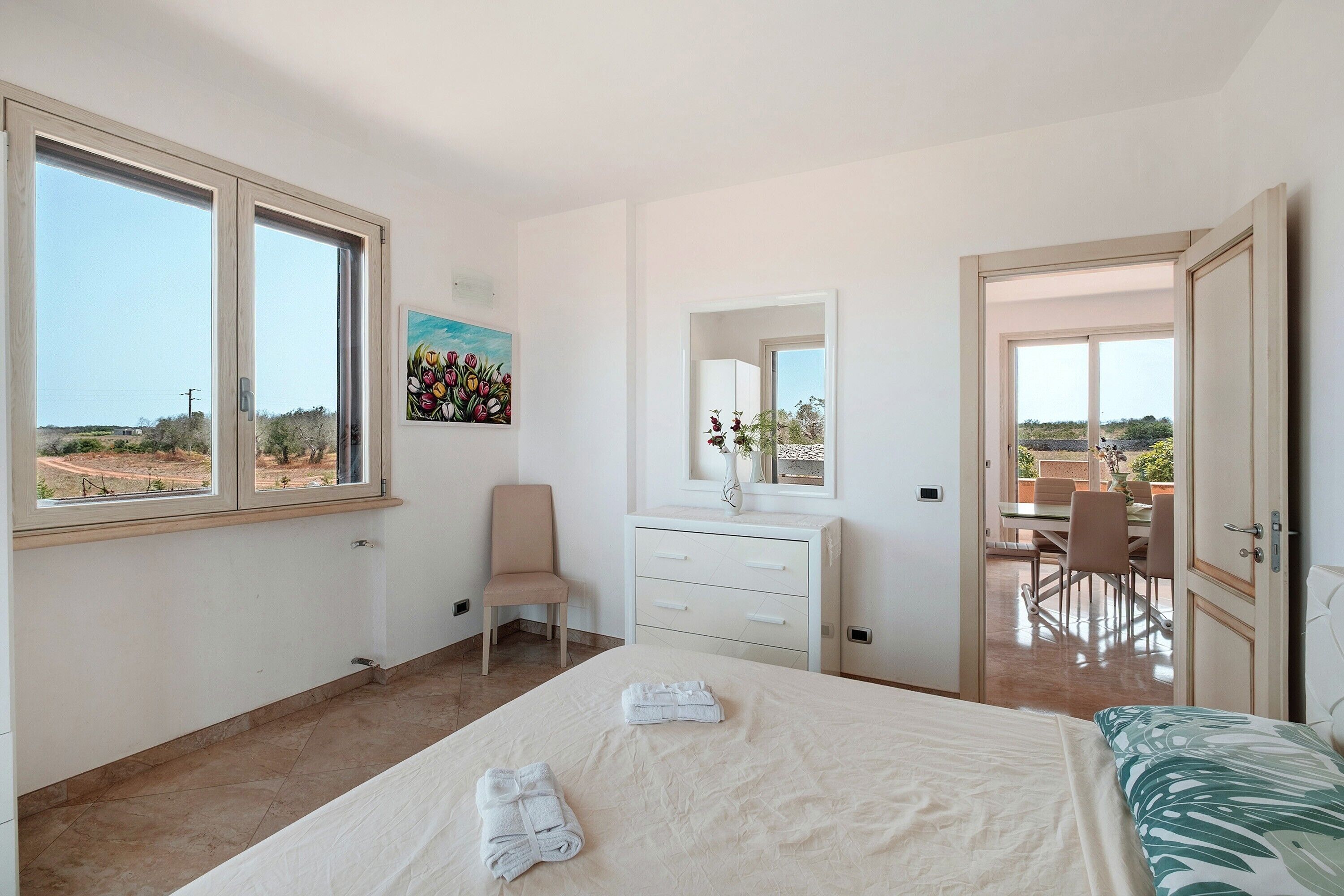 Una camera da letto con un letto, una sedia, una cassettiera e una finestra.
