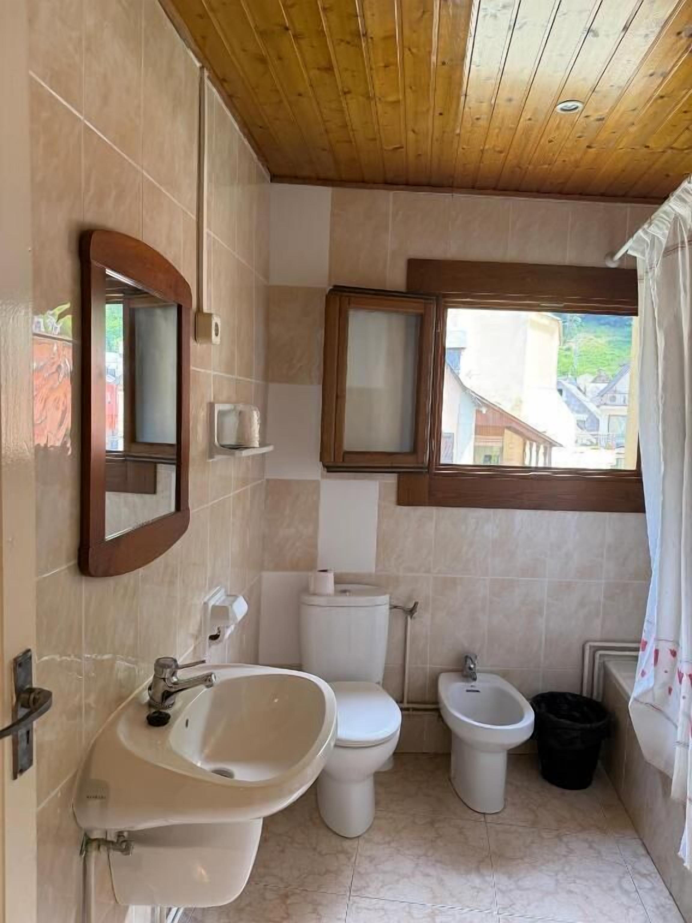 Un baño con lavamanos, inodoro, bidé y ventana con vistas.