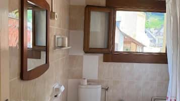 Un baño con lavamanos, inodoro, bidé y ventana con vistas.