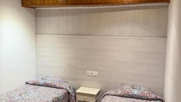 Quarto com duas camas, teto de madeira e uma pequena mesa de cabeceira.