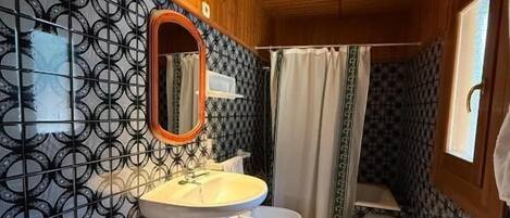 Un baño pequeño con techo de madera, un lavamanos, dos inodoros y una zona de ducha.