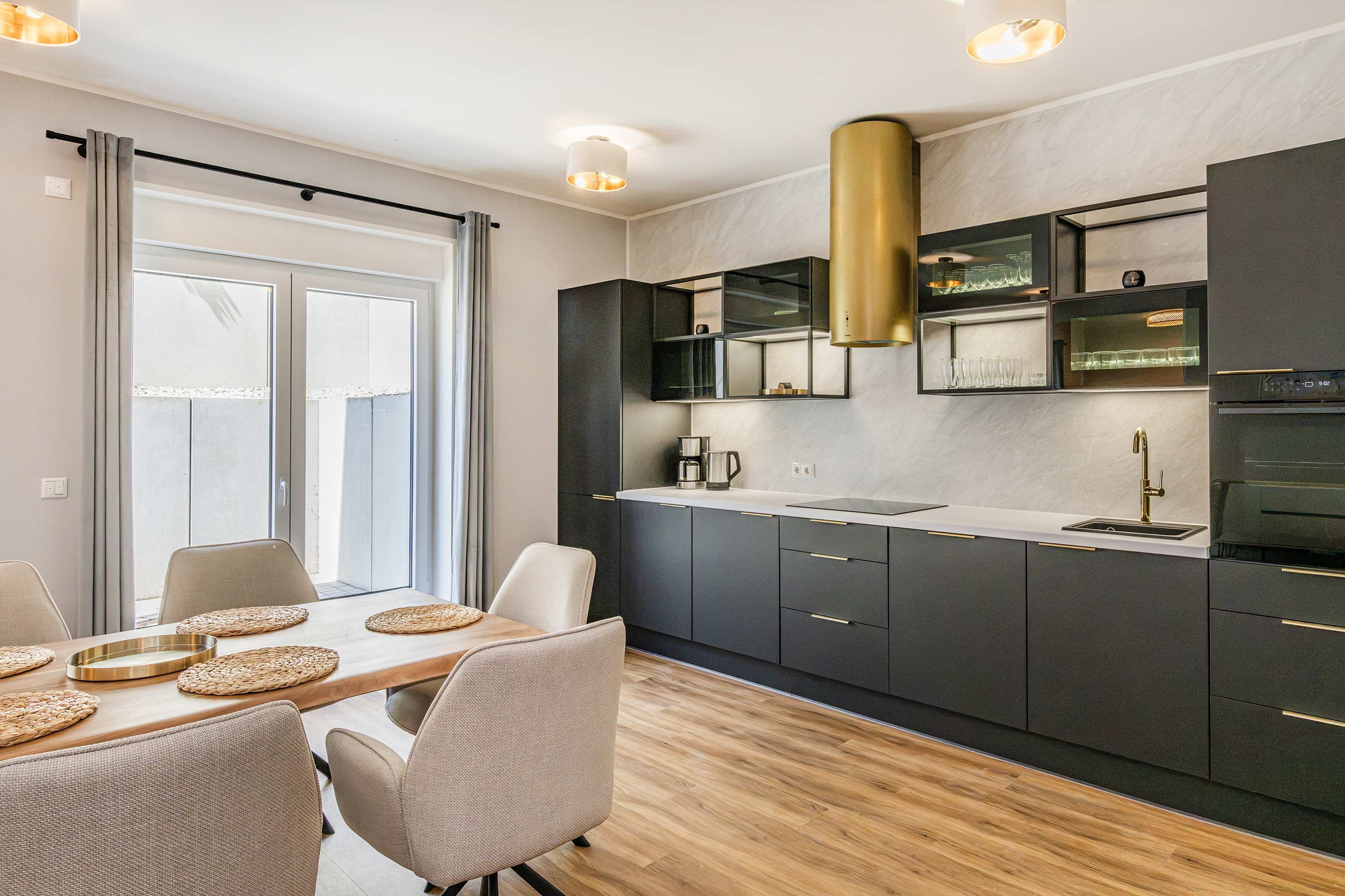 A modern kitchen with dark cabinetry, a stainless steel sink, and a built-in oven.