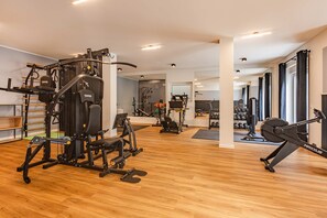 A modern gym with various exercise equipment, wooden flooring, and a large mirror. - Spacious vacation rental with a sauna on the lagoon for the whole family (Zirchow)