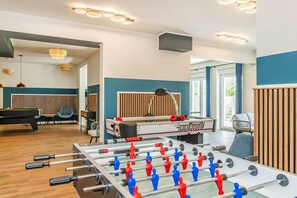 A modern indoor space with a foosball table, a pool table, and a seating area with a view of the outdoors. - Spacious vacation rental with a sauna on the lagoon for the whole family (Zirchow)