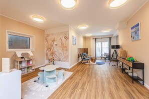 A spacious room with a wooden floor, a round table, and a bookshelf. - Spacious vacation rental with a sauna on the lagoon for the whole family (Zirchow)