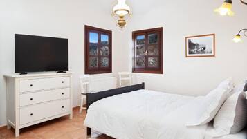 A bedroom with a bed, a dresser, a chair, and two windows with curtains.